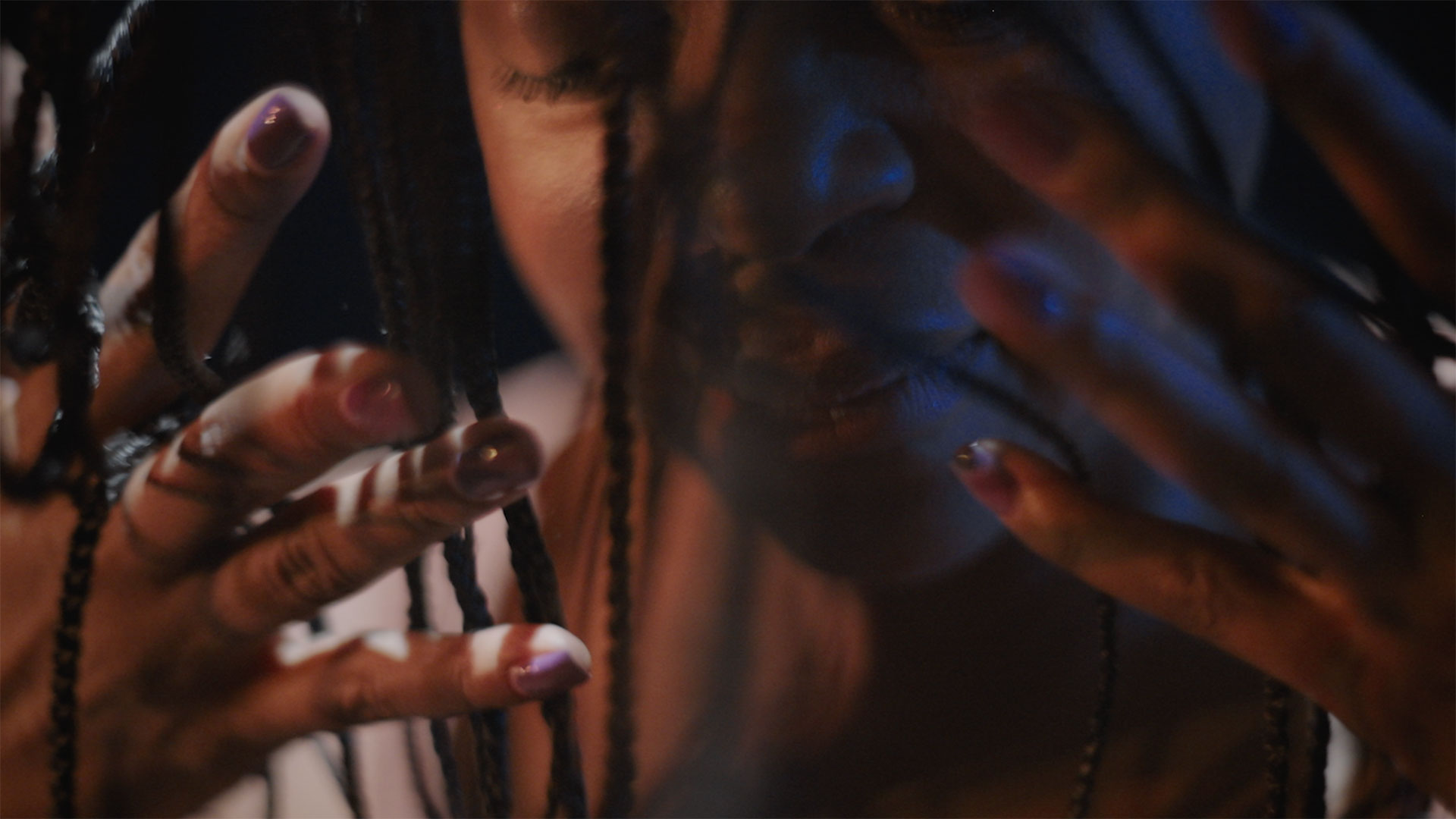 through outstretched open palms, and long hair braids, an extreme closeup of a woman's face deep in thought or pain