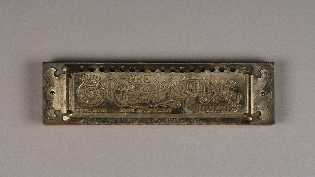 A harmonica with the words 'The Roosevelt Rough Rider Concert' engraved