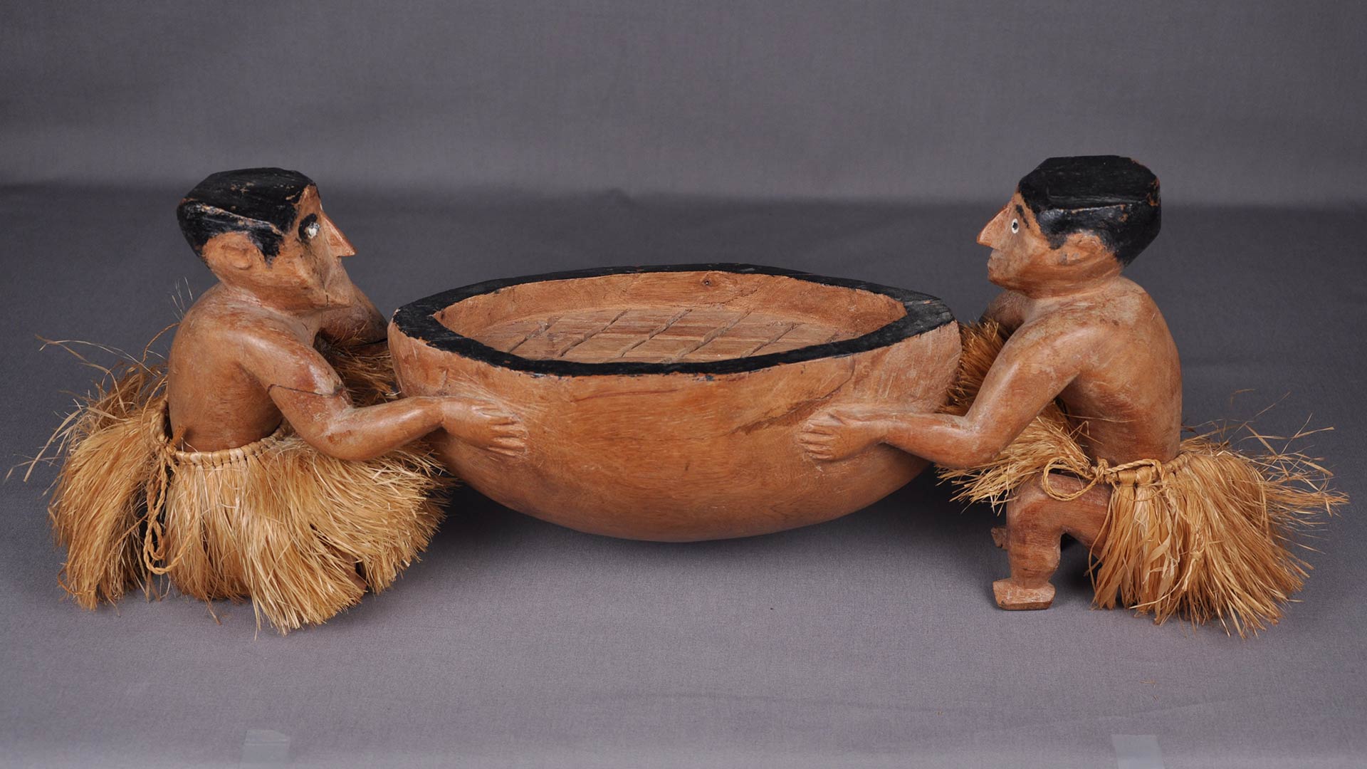 an artifact of two men holding a bowl on either side of the bowl