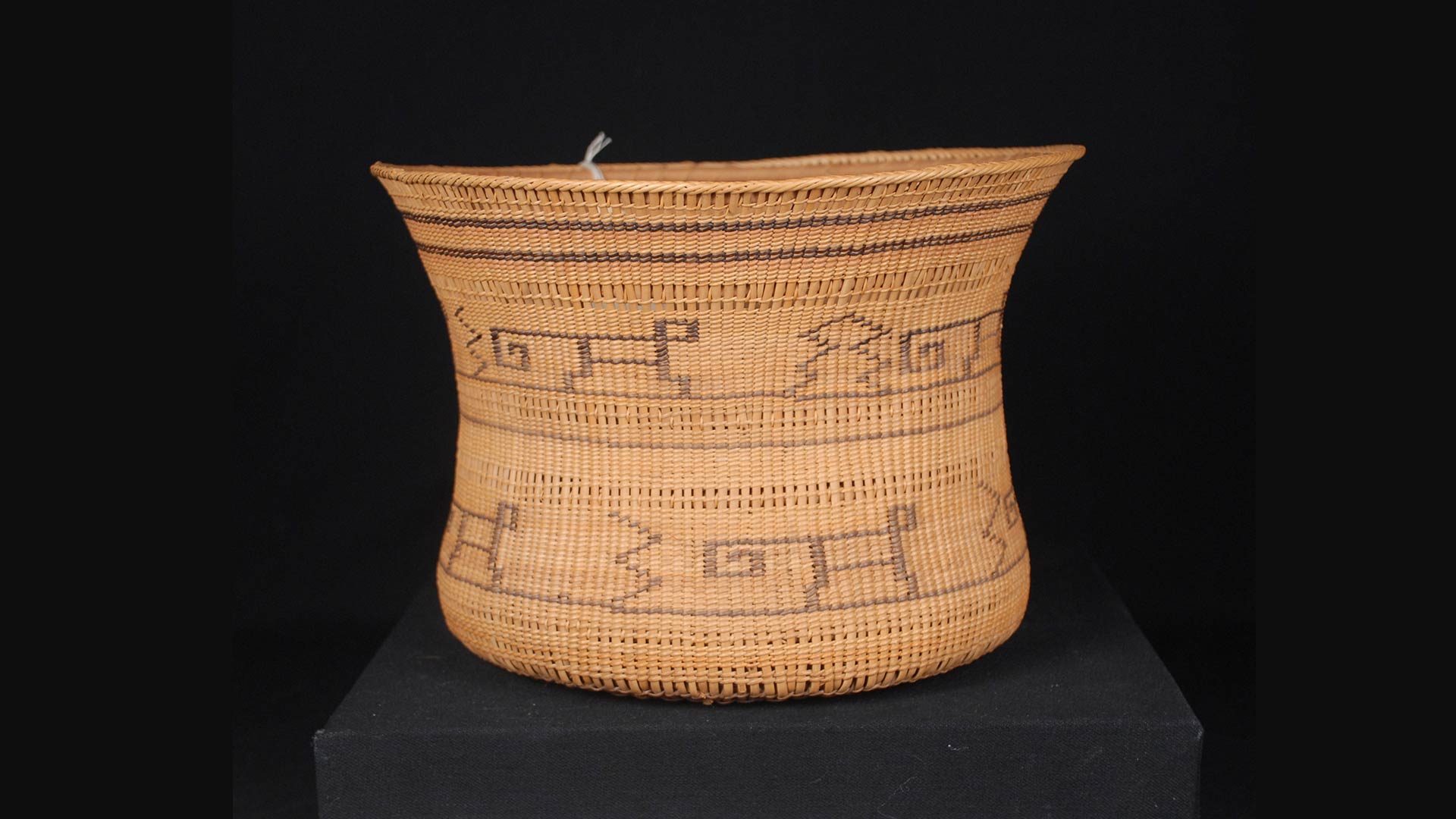 woven basket with glyphs around its perimeter