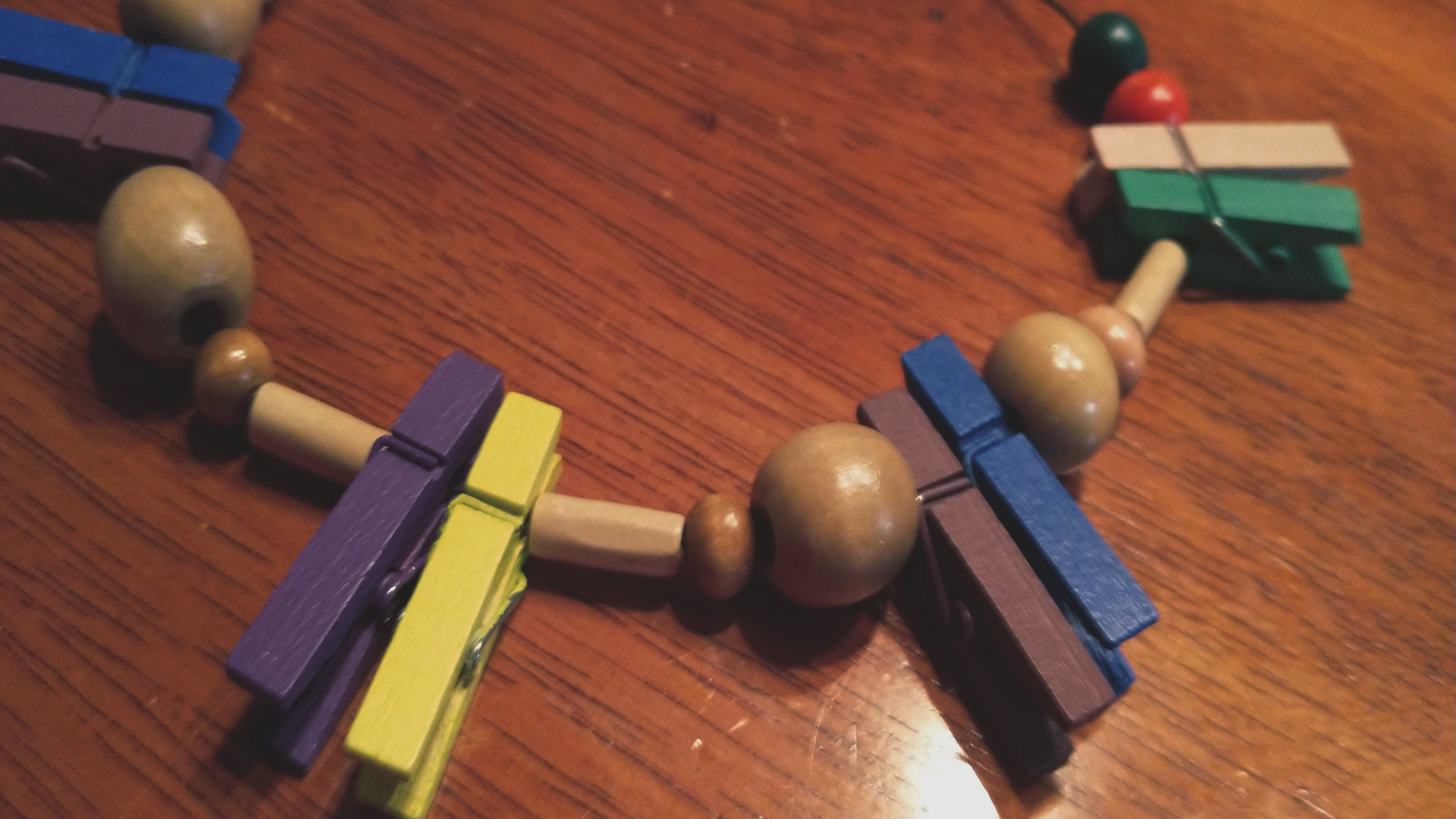 Closeup of handmade necklace made of different colored wooden beads and clothespins on a table