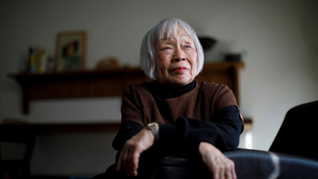 a woman with gray hair sitting on a chair looks pensively to the right