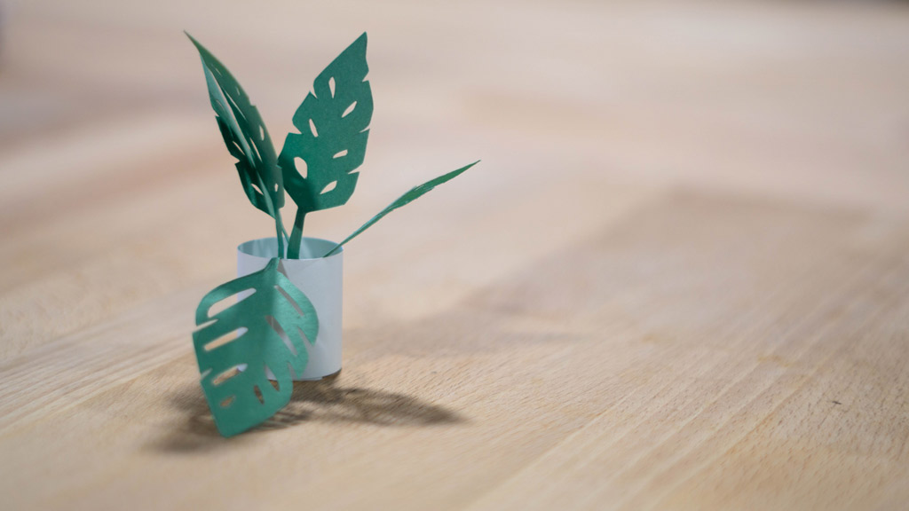Fake plant made out of green paper with a pot made out of white paper 